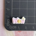 Dettaglio di charm WOW in resina rosa con faccina gialla su tappeto graduato - Mini Piastra WOW