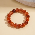 Detailed view of red agate beaded bracelet with natural textures on warm beige background - Brown