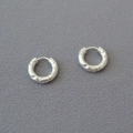 Macro detail of silver hammered texture on circular hoop earrings with a metallic finish - Silver