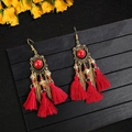 Bohemian long tassel earrings with red beads and golden feather charms on black background - Red Gem Tassel