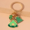 Detailed close-up of green enamel frog and lotus leaf pendants on a golden keychain ring - Frog Leaf