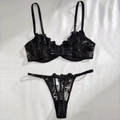 Flat lay of black floral lace lingerie set with embroidered bra and thong on silk - S / Black