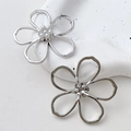 Detail of silver hollow flower earrings with white pearl centers on a textured stone tray - Single Piece / Silver