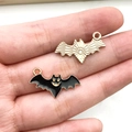 Detailed close-up of golden and black enamel bat pendants held in hand for size reference - Black Bat