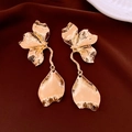 Detailed close-up of golden flower drop earrings with hammered texture on silk fabric - Flower Pendant / Gold
