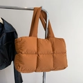 Quilted orange puffer tote bag with square pattern hanging next to a black leather jacket - Brown