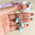 Hand holding a keychain with three teal resin mushroom charms and white polka dots - Lake Blue