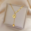 Gold titanium steel necklace featuring letter G and cube pendants on a jewelry box - Gold