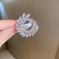 Dettaglio di una spilla a foglia argento con zirconi bianchi tenuta in mano - Argento