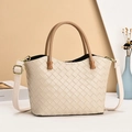 Beige gewebte Leder-Tote-Bag mit braunen Henkeln und verstellbarem Riemen auf Geometrie-Hintergrund - Cremeweiß