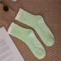 Detail of mint green fuzzy slipper socks with white faux fur cuffs and non-slip grippers - One Size / Fruit Green with Grippers