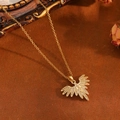 Gros plan du pendentif aigle doré serti de zircons blancs sur fond marron vintage - Style Ailes Dorées