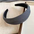 Detail eines dunkelgrauen breiten Stoff-Haarreifens auf einem Holztablett im Minimal-Stil - Grau