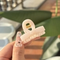 Detailed close-up of a pink resin mini cloud-shaped hair claw clip held by a hand outdoors - White Soil Cloth-Bow Style