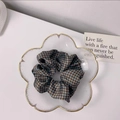 Close-up of a blue and brown houndstooth silk scrunchie in a gold-rimmed glass dish - Blue Houndstooth