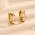 Polished gold huggie earrings with four square channel-set zircons on warm background - Gold