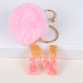 Detail of pink pom-pom keychain and resin letter N charm with gold flakes and stones - Letter N