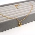 Macro shot of gold stainless steel necklace with capital U-letter pendant on velvet tray - Letter U / Gold