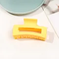 Detail view of a matte yellow rectangular hair claw clip on a stylish magazine backdrop - 8.5cm Rectangular - Matte Bright Yellow