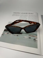 Detalle de gafas de sol cat-eye con montura de carey sobre una página de revista - Marco Carey Lentes Grises