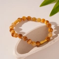 Dettaglio di perline in occhio di tigre ambra e distanziali dorati su vassoio in pietra - Bracciale Pesce con Perline Occhio di Tigre Caffè Chiaro