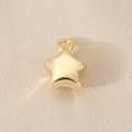 Close-up of a polished gold-plated star pendant on beige fabric for DIY jewelry making - Star Gold (18K Gold Plated)
