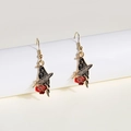 Detail of gothic raven earrings with red rose and feather charms on white stand - Pigeon Black Gold Red Rose