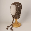 Detail of a brown mohair crochet knit hood with large mesh hollow design and long ties - Brown