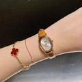 Elegant Dinimi women's quartz watch with gold oval case and brown leather strap on wrist - Leather Strap / Rose Gold Case/Caramel Strap