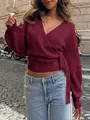Burgundy V-neck wrap knit top with elegant tie waist and long sleeves in outdoor setting - Red