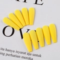 Macro view of bright yellow matte press on nails in long coffin shape displayed on paper - Goose Yellow