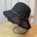 Close-up of black woven sun hat featuring wavy brim and flower detail on a metal stand - Adult 54-60 Adjustable / Black