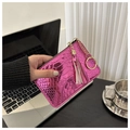 Magenta faux crocodile texture clutch bag with gold tassel keychain in hand - Rose Pink