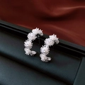 Makro-Detail von silbernen Blumenohrringen mit Zirkonia auf dunkelroter Seide - Silber