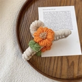 Detailed view of handmade crochet sunflower hair claw with soft plush knit texture - Orange Floral