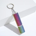 Detailed shot of rainbow rhinestone perfume bottle keychain on a white geometric stand - C16-Sparkly Rainbow