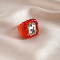 Makroaufnahme: Roter Harzring mit rechteckigem Kristall und luxuriöser Pavé-Diamant-Verzierung - Transparent Rot
