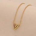 Close-up of golden V-letter pendant necklace with sparkling cubic zirconia inlay - Letter V