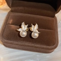 Dettaglio macro di orecchini vintage a farfalla dorati con perle in una scatola di velluto - Orecchini a lobo con perle a farfalla / Bianco (Perno per orecchino in argento)