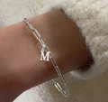Bracelet chaîne trombone argenté avec pendentif lettre M porté par une femme - Lettre M / Couleur Acier