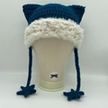 Detail view of blue crochet cat ear hat with white plush trim and star tassels - Malachite green