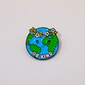 Detail of a cartoon enamel pin featuring a smiling Earth and Be Kind slogan - Be Kind Earth With Flower Crown Round Pin (C2261)