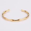Dettaglio ravvicinato di un bracciale rigido dorato a forma di bambù da un'angolazione di 45° - Oro