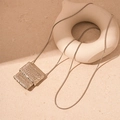 Macro shot of silver woven square pendant with fine snake chain on stone surface - Silver Woven Bag Style