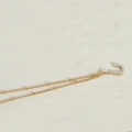 Golden U-shaped necklace with embedded pearls on a delicate beaded chain - Letter U