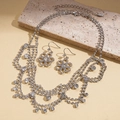 Detailed macro view of layered rhinestone necklace and snowflake pendant earrings - Silver