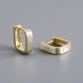 Close-up of modern rectangular huggie earrings with a brushed matte metal finish - Gold