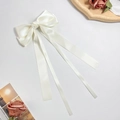 Detail der cremeweißen Satinschleife Haarspange mit langen Bändern auf elegantem Grund - Beige