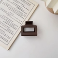 Close-up of matte dark brown square hair claw clip placed on an open book - Matte Dark Coffee