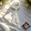 Pañuelo estrecho de seda blanca con corazones negros anudado en fondo suave - Corazón Crema